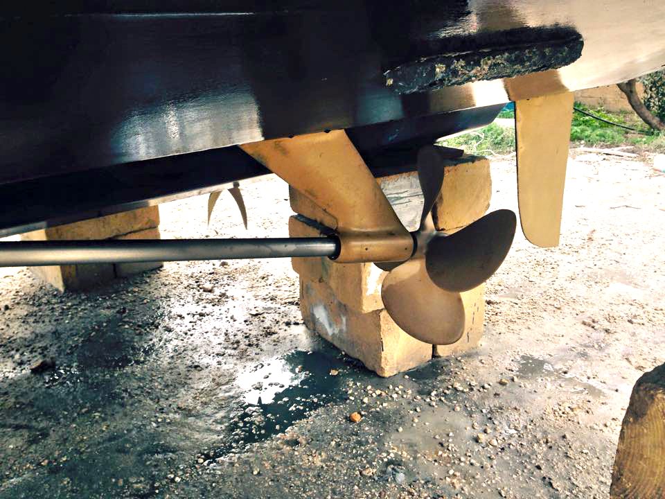 Mobile dustless blasting for boat hull restoration, featuring a clean brass propeller and shaft.